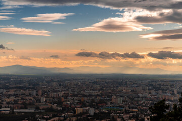 a city below the cloudy sky in the middle of sunset