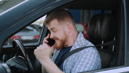 Happy male driver talking on the smartphone in the car. Slow motion