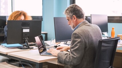 Manager using laptop at desk in coworking workspace