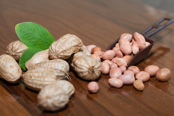 Fresh peanuts and leaves in bowl on wooden table