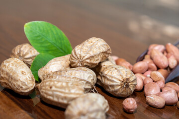 Fresh peanuts and leaves in bowl on wooden table