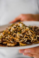 A very detailed and close-up photo of a pempek lenggang dish, topped with pempek vinegar and sprinkled with small, delicious cucumber pieces.