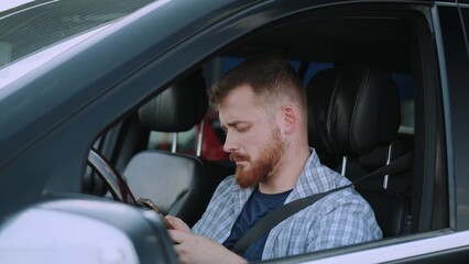 Young man typing message on the smartphone in the car. Slow motion