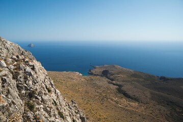 Majestic rocky cliff formation in a natural landscape, with a bright blue sky in the background