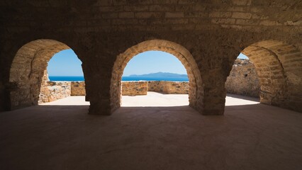 Empty arched structure overlooks the ocean on a sunny day