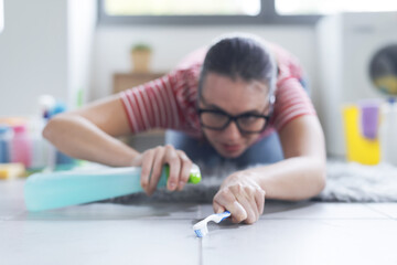 Woman cleaning the bathroom floor using a toothbrush