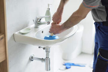Repairman unclogging a bathroom sink