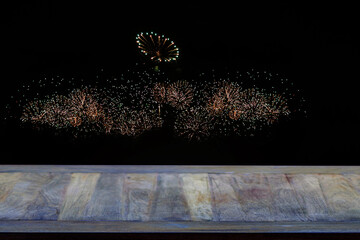 Empty wooden table with background.Colorful fireworks of red, orange, green, and yellow filled the...