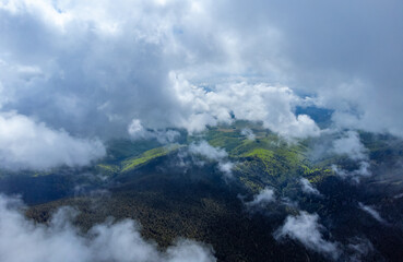 Aerial view of clouds over forested mountains