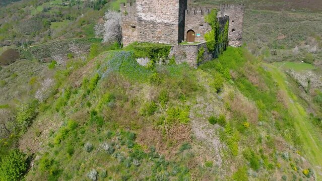 Aerial footage of the historic Doiras Castle on the green hill on a sunny day in Cervantes, Spain