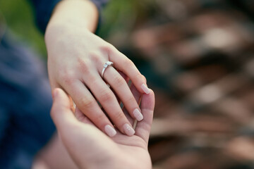 Couple, engagement ring and nature with holding hands in closeup for proposal with love, surprise...