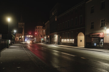 ulica w małym mieście w nocy z asfaltową drogą i sklepikami