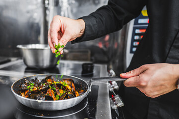 Close-up of a chef garnishing food with herbs in a pan, showcasing culinary skills and fresh...