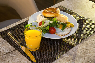 A hearty breakfast of eggs, broccoli rolls, olives, tomatoes and herbs combined with orange juice.