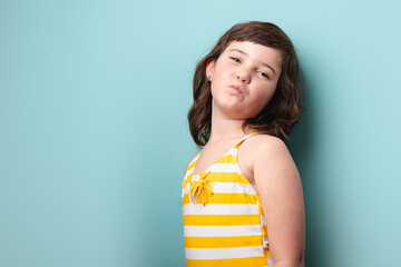 Young girl posing confidently in a striped yellow swimsuit