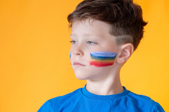 Young boy with colorful flag painted on his cheek