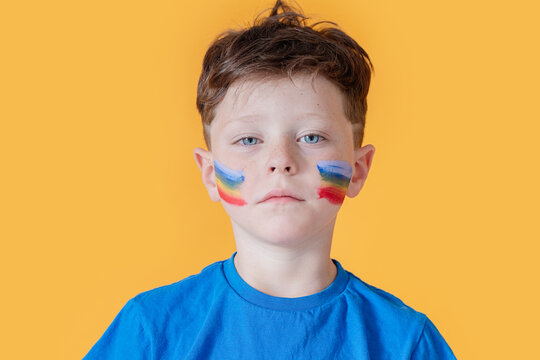Young boy with colorful face paint on a yellow background