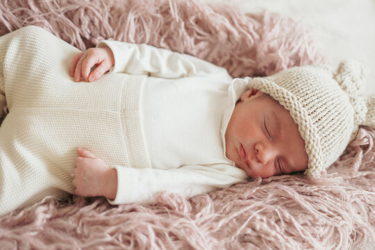 Peaceful newborn sleeping on soft pink blanket