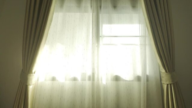 Beautiful golden curtain window scene along with glowing light of evening atmosphere Warm yellow tones peeking through silk curtains or curtains inside. 4K slow motion footage