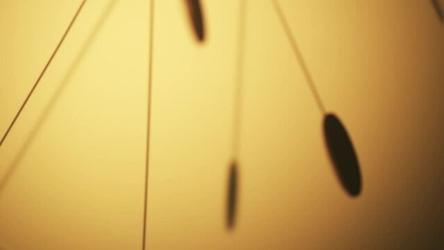 Slow motion of Golden pendulum swinging with shadow on sunny yellow wall