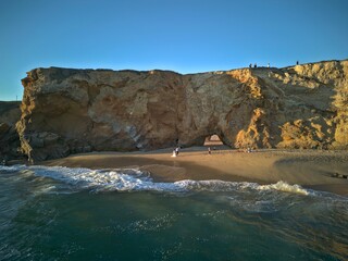 Tranquil beach with a large rocky outcrop in the distance in Panther Beach, Santa Cruz, California.