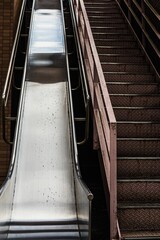 Vertical shot of a metal escalator next to a staircase in a modern setting