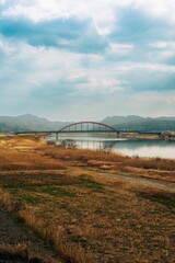 Scenic view of a river with a bridge crossing it, situated against the backdrop of a lush green hill
