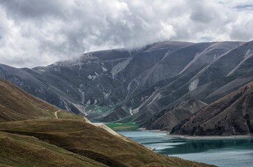 Scenic view of a lush green valley surrounded by rolling hills, with a mountain lake in background