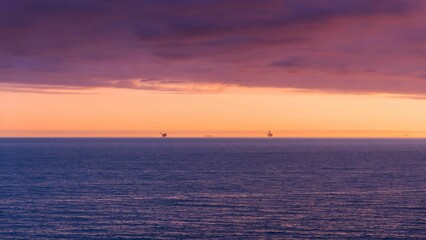 dark clouds over the ocean as the sun sets in the distance