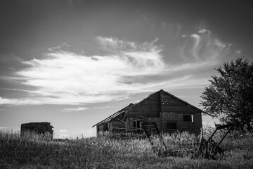 an old wooden building on a plain with trees and grass