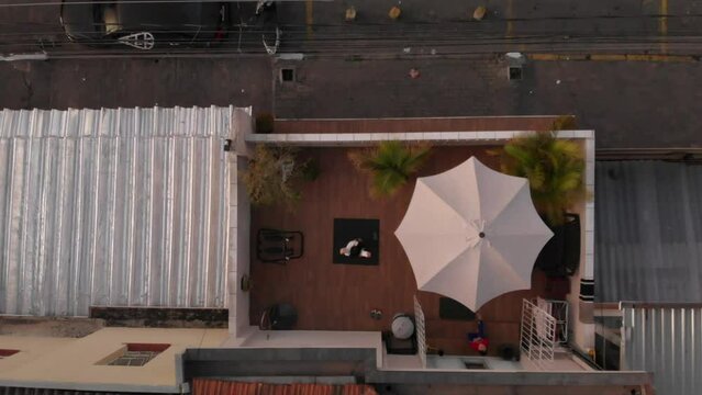 Aerial top view video of a girl meditating on a rug on the roof of a building next to the road