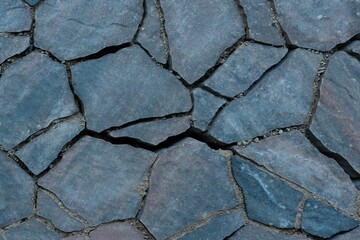 Closeup of a gray stone wall, with the texture and pattern of the stones visible
