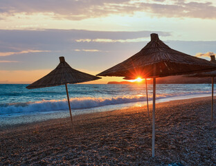 Summer sunset beach with strawy sunshades (Albania).