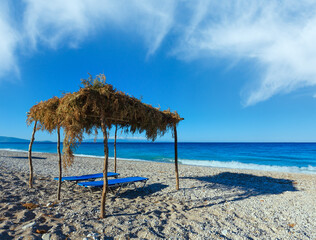 Summer morning pebbly beach with sunbeds and canopy (Albania).