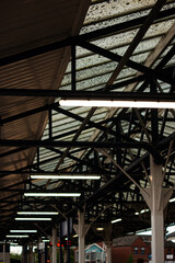 A train station with a lot of lights. Scene is busy and bustling