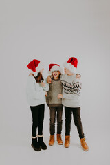 Obraz premium Christmas Kid Joy: Brothers and Sister with Red Hats Smiling and Having Fun for Christmas 