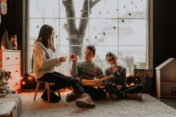 Kids holiday magic: Two brothers and sister playing with lanterns by the Christmas tree
