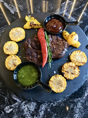 A delicious dish featuring a succulent steak and juicy corn on the cob served on a plate. This classic cuisine pairs perfectly with a squeeze of lemon