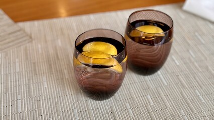 Two clear glasses of water with lemon slices on the table in the restaurant. Pleasant atmosphere. Close-up
