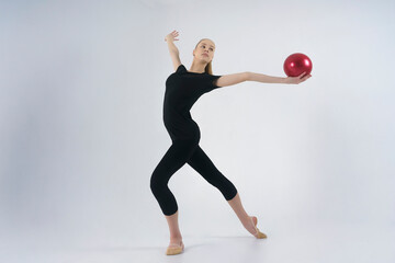 young gymnast in a photo studio shows the elements of exercises with a ball