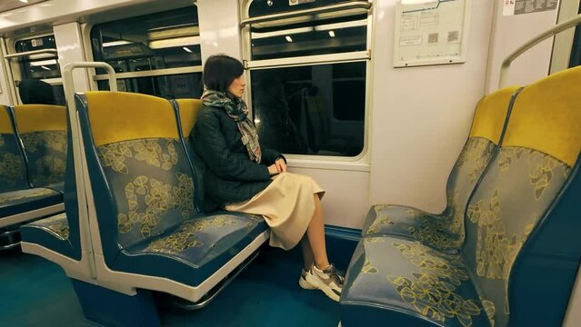 Woman sitting at metro train and looking into window in Paris in early morning. Public transport in Paris, France