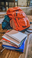 A backpack with notebooks and textbooks, sits open on the floor, ready for the first day.
