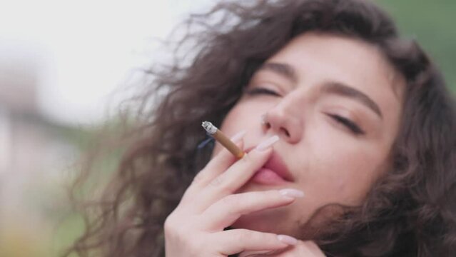 Portrait of a beautiful woman in summer who smokes a cigarette slow motion