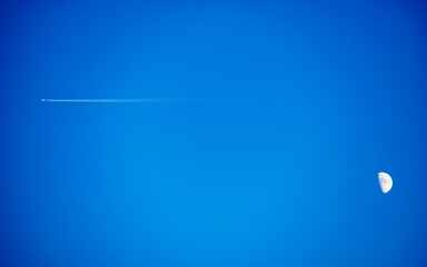 Airplane flying across sky with moon