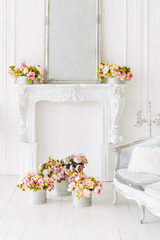 Soft home decor, decorative fireplace, vases with flowers and mirror. White wall background, Interior.