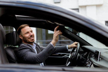 Businessman enjoys sunshine in a luxury convertible on a bustling city street