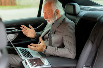 Senior businessman expressing surprise during a video call in his car