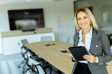 Fototapeta premium Confident businesswoman holding tablet in modern office conference room during daytime