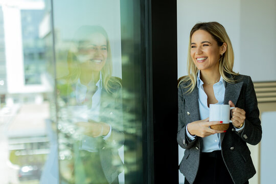 Businesswoman enjoys a coffee break in a modern office building on a sunny day