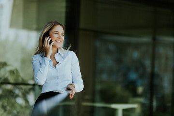 Young professional woman talking on a phone call outdoors on a sunny day